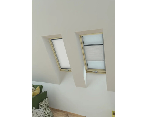 Twee dakramen met zonwering in een lichte kamer.