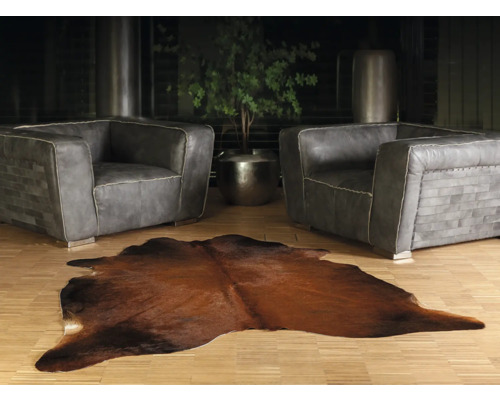 Woonkamer met twee grijze leren fauteuils en een bruin koeienhuidtapijt