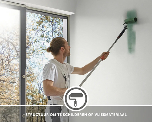 Een man schildert een muur met een verfroller aan een telescopische steel