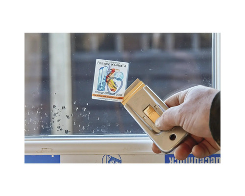 Persoon verwijdert sticker van Pilkington K Glass met een schraper