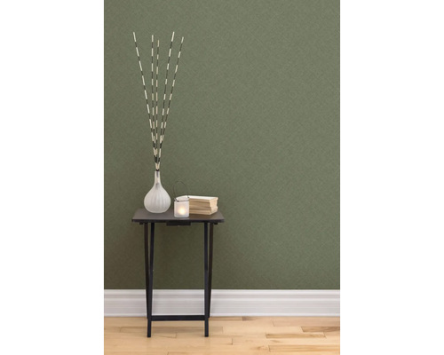 Decoratieve scène met tafel, vaas, kaars en boeken tegen een gestructureerd behang