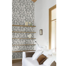 Woonkamer met patroonbehang, houten planken en witte bank.