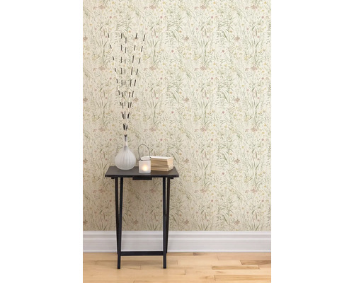 Een close-up van een muur met bloemenbehang en een bijzettafel met decoratieve items zoals een vaas, een theelicht en boeken.