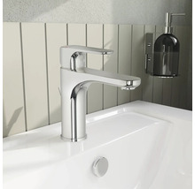 Wastafelkraan van chroom op een witte wastafel met zeepdispenser