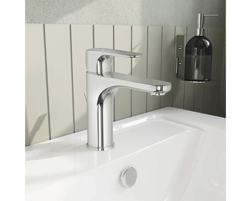 Wastafelkraan van chroom op een witte wastafel met zeepdispenser