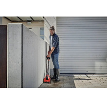 Man reinigt een betonnen muur met een elektrische borstel buitenshuis