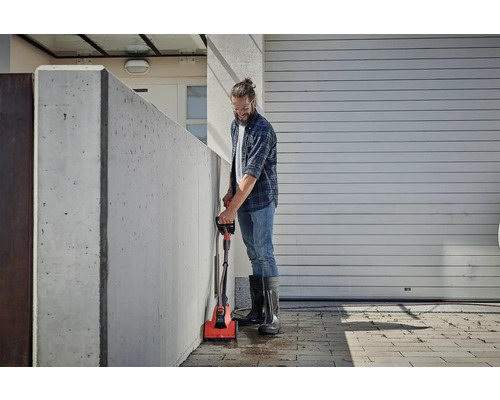 Man reinigt een betonnen muur met een elektrische borstel buitenshuis