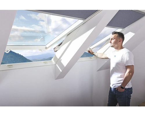 Man opent een dakraam met uitzicht naar buiten