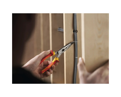 Persoon die met een tang een draad aan een muur bevestigt