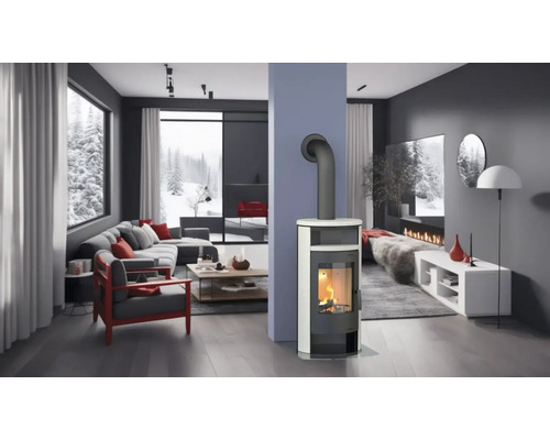 Lichte woonkamer met kachel, bank en uitzicht op een besneeuwd landschap.