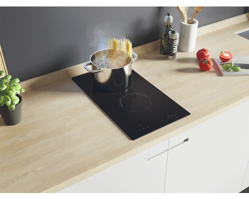 Spaghetti koken op een zwarte kookplaat in een lichte keuken.