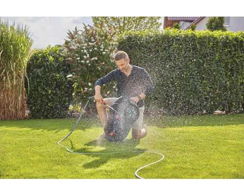 Man knielt op gazon en besproeit met gazonsproeier