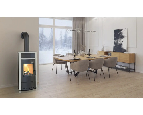 Woonkamer met houtkachel, eettafel en stoelen onder een hanglamp.