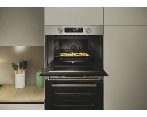 Inbouwoven met open deur en een bakplaat vol eten in de oven