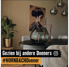 Decoratief interieur met eettafel, vaas, kamerplant en schilderij aan de muur.