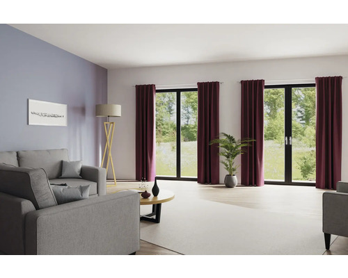 Woonkamer met bank, vloerlamp, salontafel, kamerplant en gordijnen voor ramen.