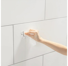 Montagevoorziening op een betegelde wand met een hand die het reinigt