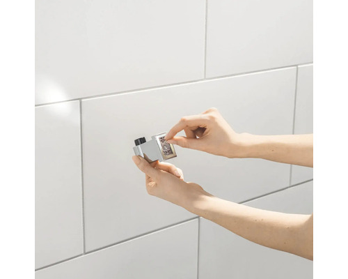 Installatie van een magnetische deurvanger op een betegelde muur.