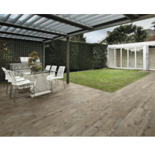 Terras met houtlook terrastegels, tafel, stoelen en barbecue onder een overkapping