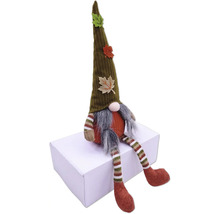 Decoratieve kabouter met muts en herfstbladeren zit op een doos