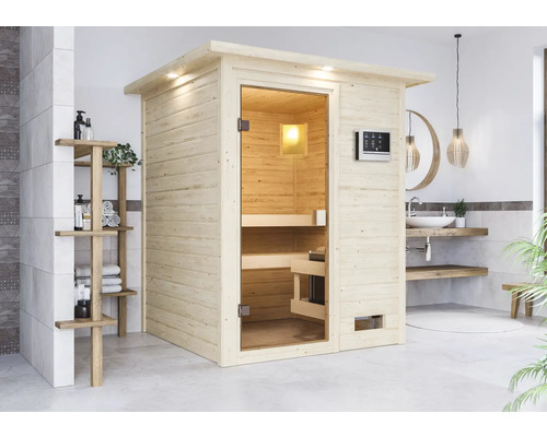 Lichte houten sauna met glazen deur en bedieningspaneel in een badkamer met wastafel en rek.
