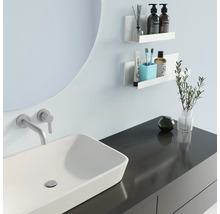 Lichte badkamer met wastafel, spiegel en witte wandplanken voor badkamerbenodigdheden