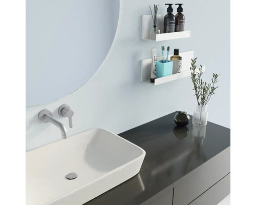 Moderne badkamer met wastafel, spiegel en wandplanken voor het opbergen van badkamerartikelen.