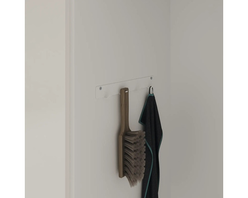 Aan de wandhouder hangen een veegborstel en een handdoek.