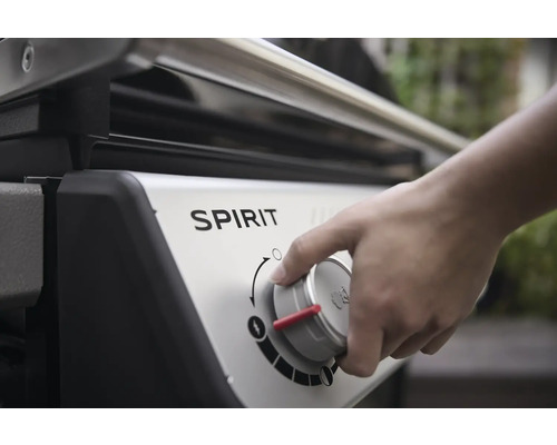 Close-up van een Spirit gasbarbecue met een hand die de temperatuurregelaar bedient.