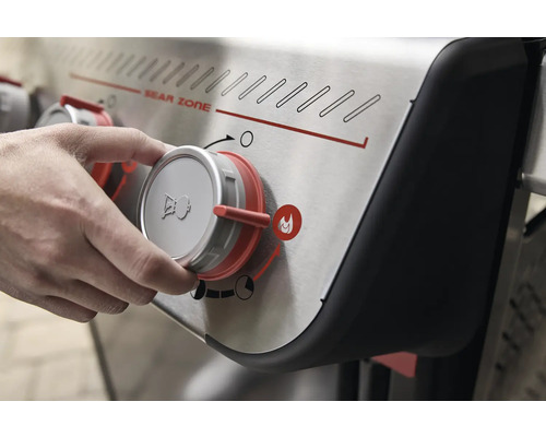 Bedieningspaneel van een barbecue met een hand die aan een knop draait