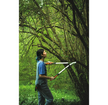 Vrouw gebruikt een takkenschaar in de tuin om takken te snoeien