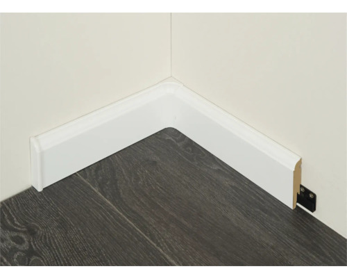 Hoek met witte plinten en donkere houten vloer