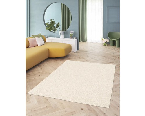 Beige hoogpolig tapijt in een woonkamer met een gele bank en een ronde spiegel.