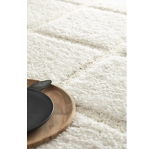 Detailweergave van een wit hoogpolig tapijt met houten dienblad en servies