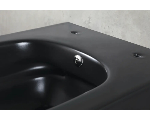 Detailopname van een zwarte wastafel met een ronde afvoerplug.