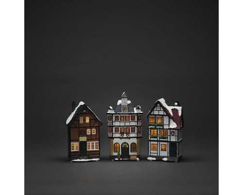 Drie decoratieve, verlichte vakwerkhuizen met sneeuw op de daken als kerstdecoratie.