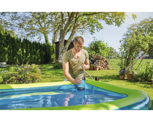 Man gebruikt een dompelpomp om water uit een zwembad in de tuin te pompen.