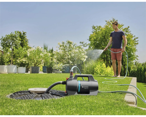 Tuin met sproeierpomp, waterreservoir en persoon met tuinslang