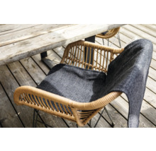 Tuinopstelling met rotan tuinstoel en zitkussen onder houten tafel
