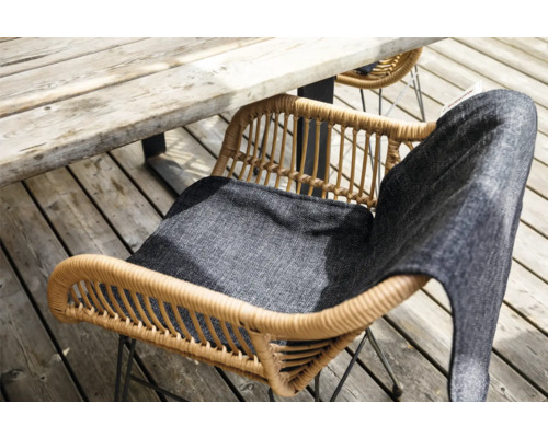 Tuinopstelling met rotan tuinstoel en zitkussen onder houten tafel