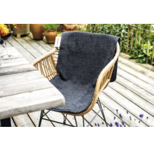 Rotan tuinstoel met grijs zitkussen op een houten terras