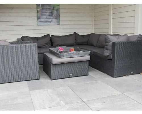 Grijze tuinlounge met tafel en kussens op een terras