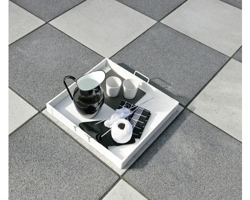 Dienblad met kan, kopjes en breiwerk op vloertegels