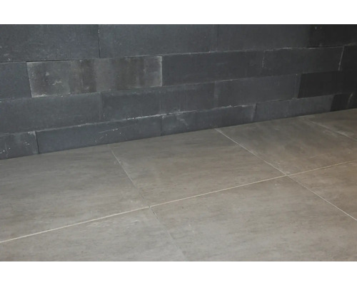 Wand met natuursteenstrips en vloertegels.