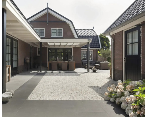 Buitenkant met terras, grind en tuinmeubelen voor een bakstenen huis