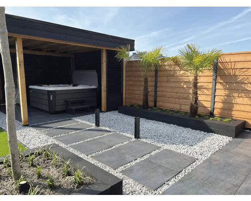 Tuinscene met overdekte whirlpool, stenen pad en houten schutting