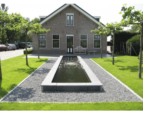 Buitenaanzicht van een huis met rechthoekige tuinvijver en grindpad