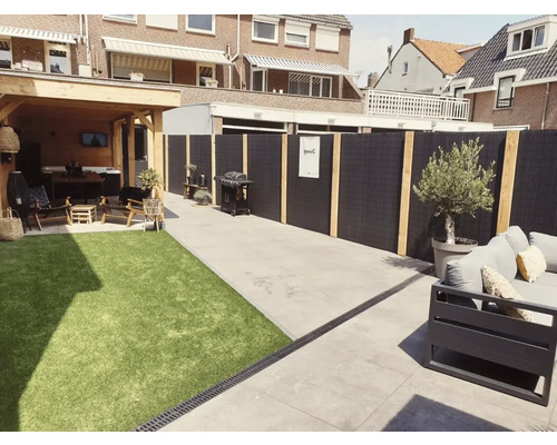 Buitenkant met gazon, barbecue, loungemeubels en privacyscherm
