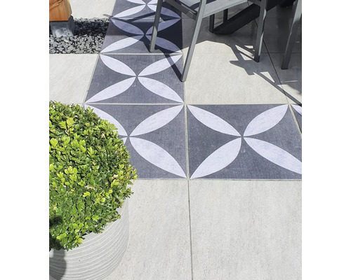 Terras met grijs-witte vloertegels met grafisch patroon, tafel en potplant