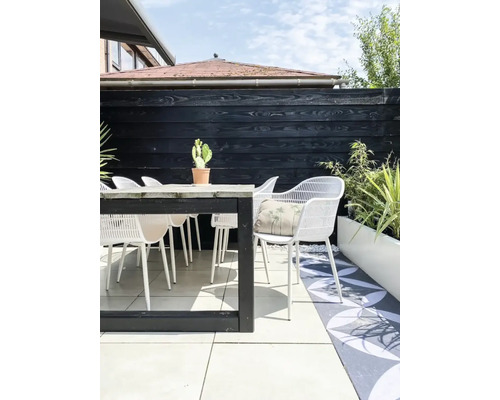 Terras scene met houten tafel, witte stoelen, cactus en decoratief kussen